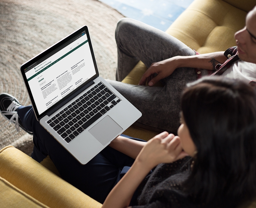 Two students on laptop with the MSU Department of Pharmacology and Toxicology website pulled up