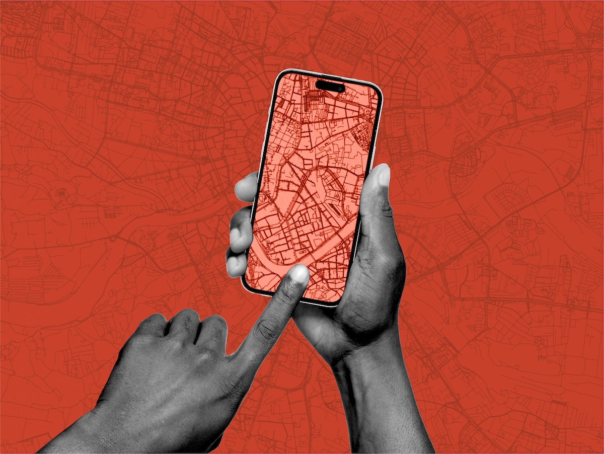 A pair of hands hold a mobile phone that displays a red map grid image. 