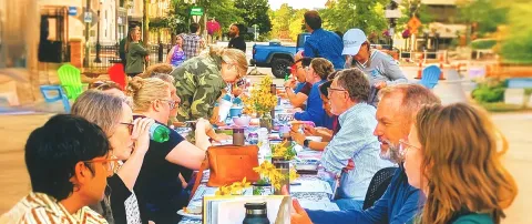 People seated at a long table in downtown Lansing
