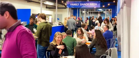 Crowd of people mingling at a family snack area